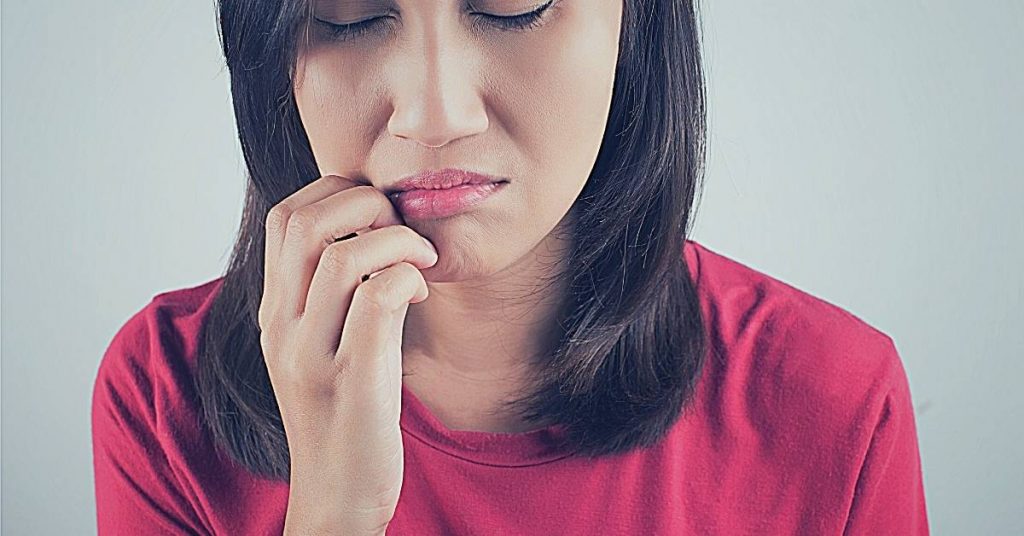 a person touching their chin in apparent discomfort, possibly indicating symptoms of dental pain or infection.