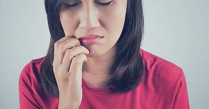 a person touching their chin in apparent discomfort, possibly indicating symptoms of dental pain or infection.