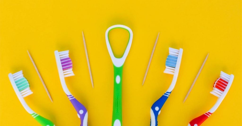 a collection of colorful toothbrushes and an interproximal brush with a tongue scraper, highlighting oral hygiene tools for a morning and evening routine