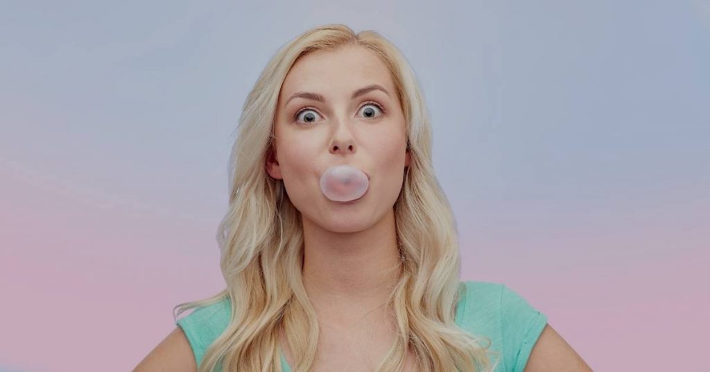 a woman blowing a bubble with sugar-free gum against a pastel background