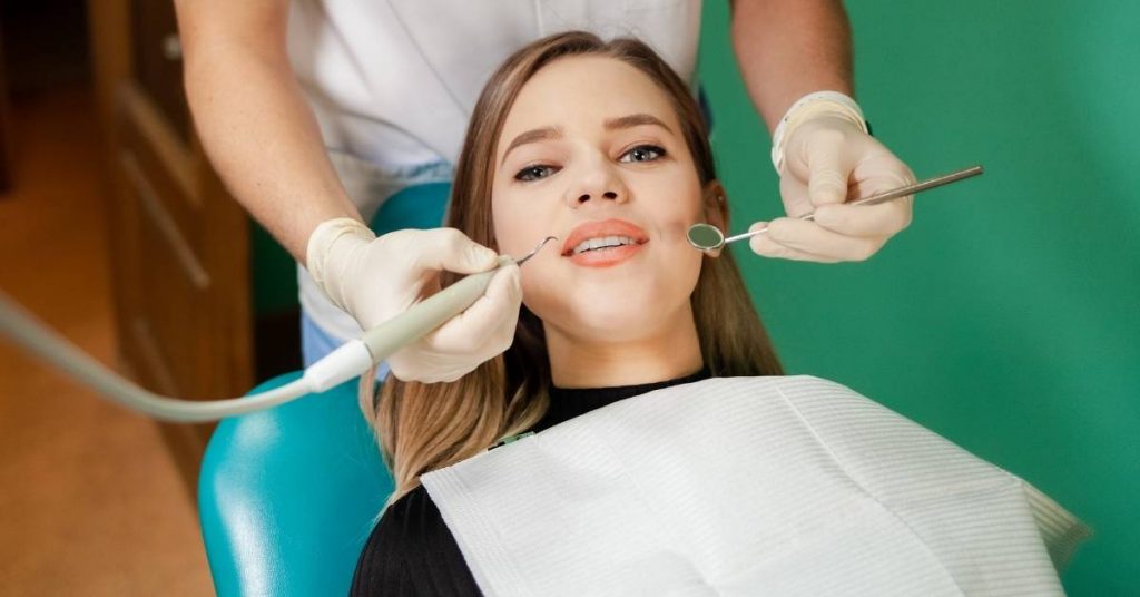 a dentist using dental tools to examine a patient’s teeth for tartar during a professional oral health checkup