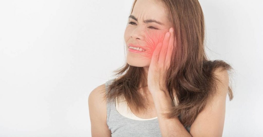 a person holding their cheek, indicating pain or discomfort near the gum area, suggestive of advanced gum disease symptoms