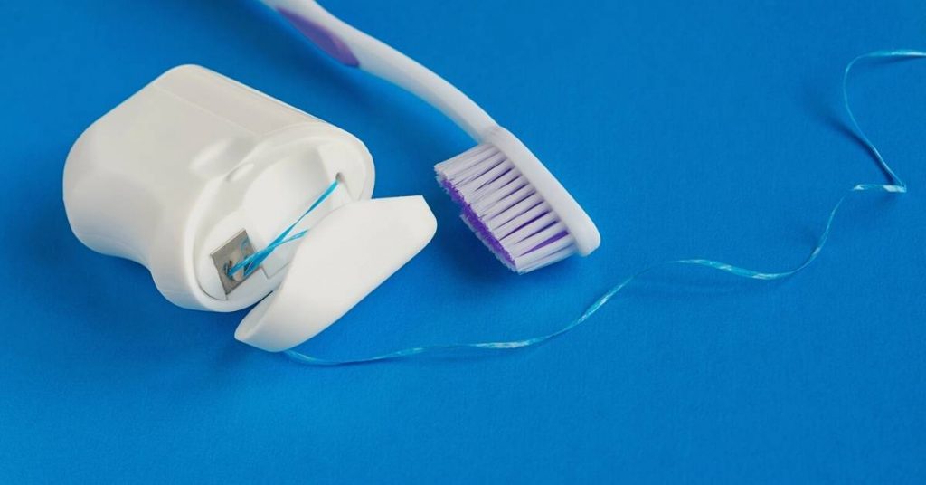a close-up of an electric flosser with a purple handle and attached floss threader for effective daily flossing