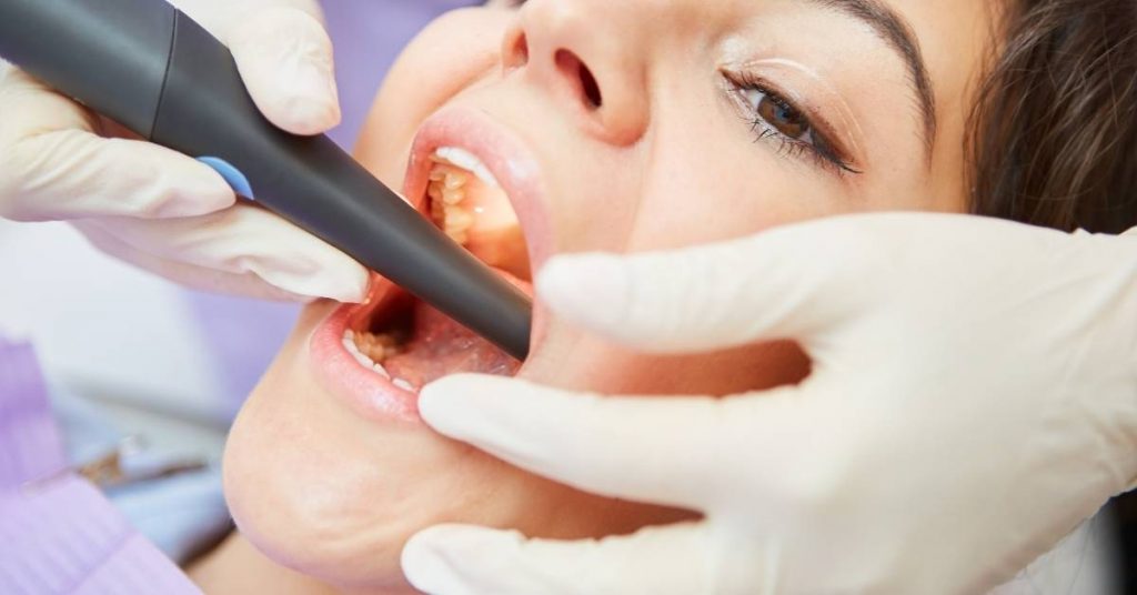 a dentist using a dental explorer to examine a patient’s tooth during a root canal procedure.