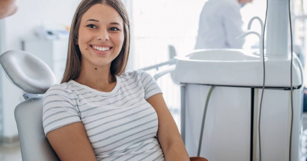 a smiling person seated comfortably in a dental chair after a gum graft consultation