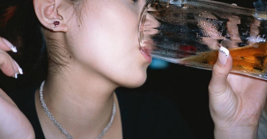 a person drinking from a frosty beer glass, showcasing potential dental impact.
