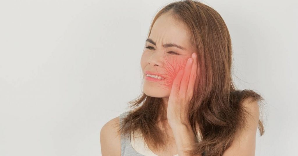 a person holding their cheek in pain, highlighting potential gum discomfort possibly related to tartar removal or gum treatment