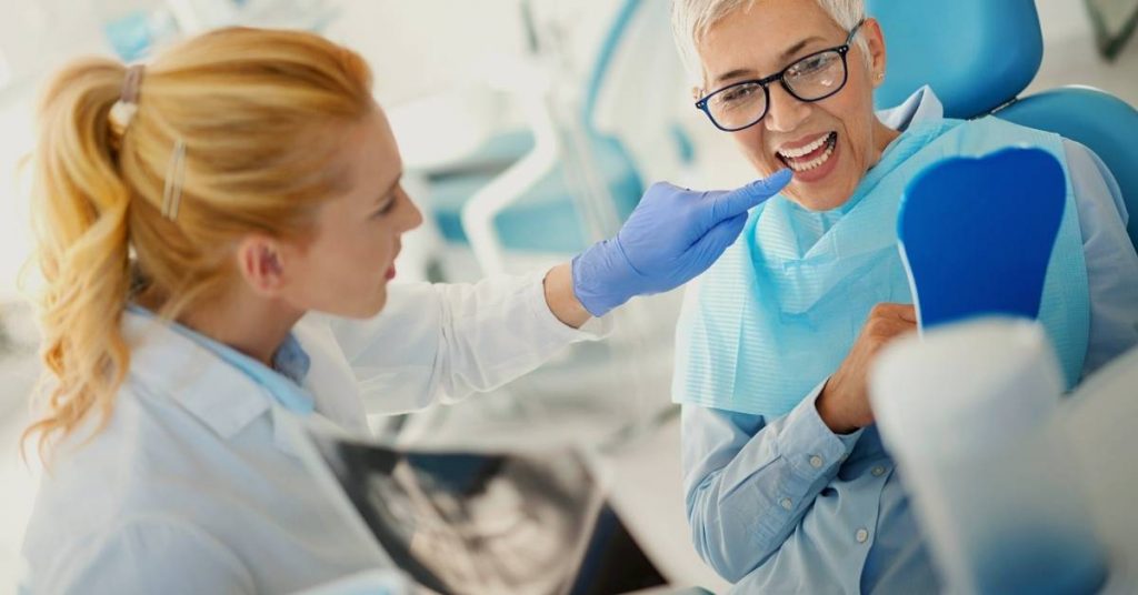 a smiling patient receiving dental care with a dentist giving a thumbs-up during a dental consultation for extensive dental restoration treatment