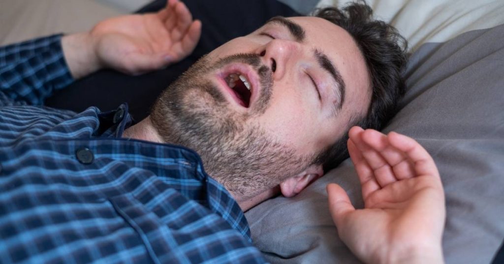 a person lying down gasping for air with mouth open, appearing distressed during sleep.