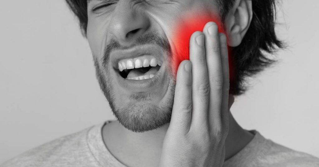 a person holding their right cheek in pain while biting down, highlighting sensitivity in the back teeth area