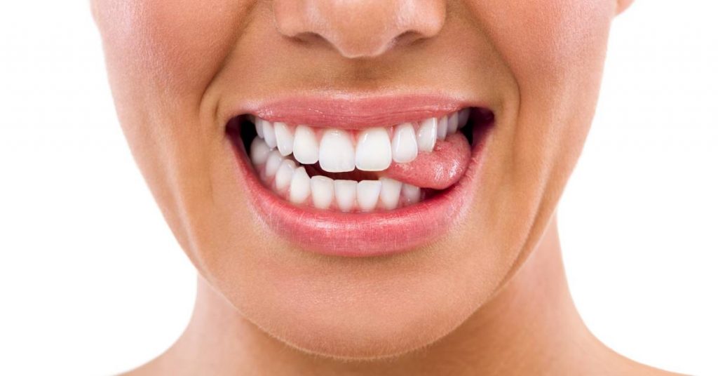 a person smiling widely showing straight, evenly aligned teeth and gums