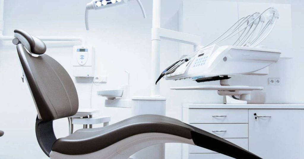 a modern dental chair with adjustable headrest and overhead dental light for oral examinations and procedures