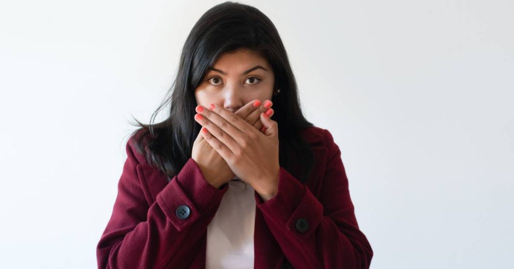 a person covering their mouth with both hands, looking surprised or concerned