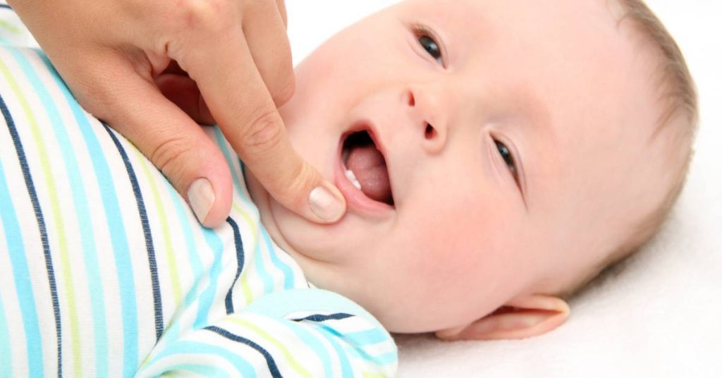 a baby’s open mouth showing primary teeth and gum area during dental development examination