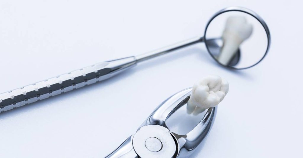 a close-up of dental tools including a surgical probe, dental mirror, and extracted tooth model on a sterile background