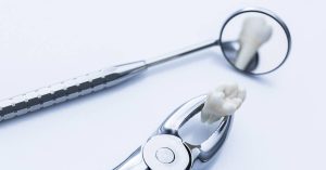 a close-up of dental tools including a surgical probe, dental mirror, and extracted tooth model on a sterile background