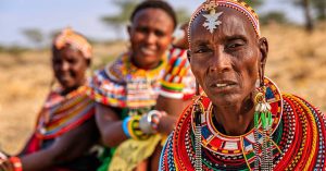 three elderly members of a traditional East African tribe adorned in colorful beaded attire, showcasing remarkable oral health.