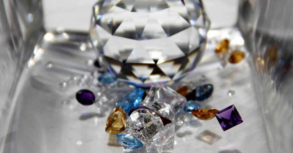 a close-up of assorted colorful gemstones and clear diamonds arranged in a display case