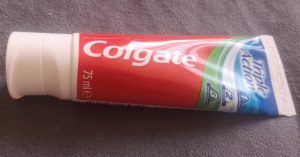 a tube of Colgate Triple Action toothpaste, 75 ml, with white cap and red packaging.